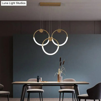 Modern gold minimalistic ring pendant light with illuminated rings suspended from wooden ceiling fixture for living room