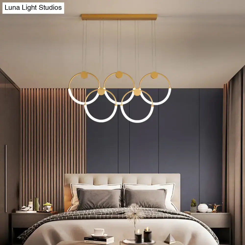 Modern gold minimalistic ring pendant light with illuminated white rings suspended from wooden ceiling fixture