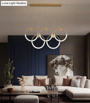 Modern gold minimalistic ring pendant light with illuminated circular rings suspended from wooden ceiling fixture