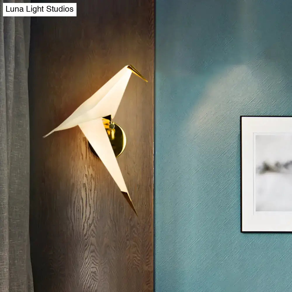 A sleek white origami bird led wall sconce with gold-toned hardware for modern bedroom lighting fixture