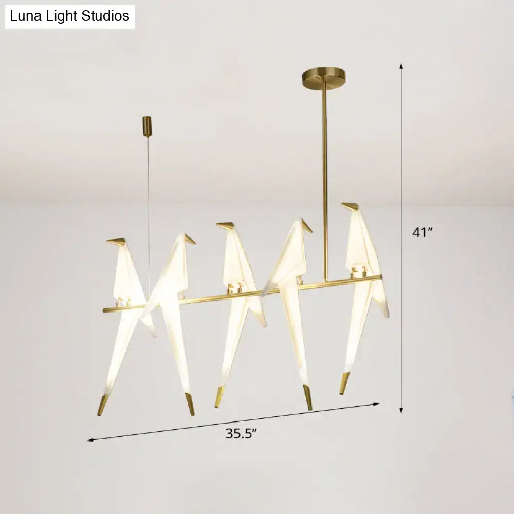 Modern gold origami bird pendant light with illuminated white paper cranes on a sleek metal frame for dining room decor
