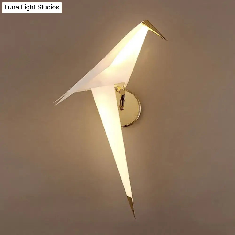 Modern gold paper crane dining room sconce with birdie plastic shade, white translucent body, and gold-toned wall lamp accents