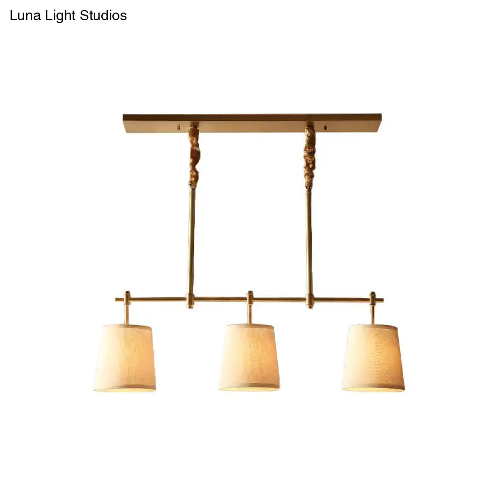 Brass-finished modern gold pendant lamp with three textured off-white fabric shades for dining room lighting
