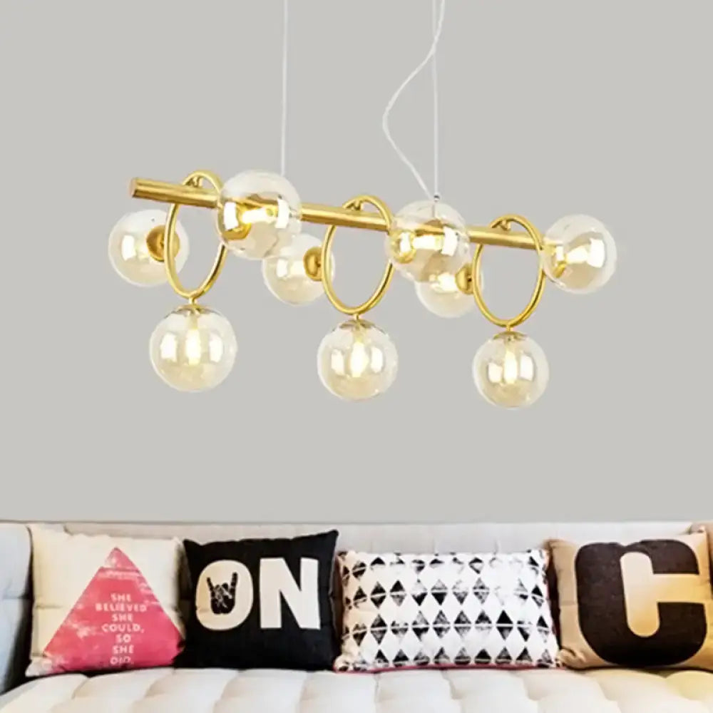 Gold-toned modern decorbites pendant light with nine clear cognac glass globe bulbs suspended from central rod