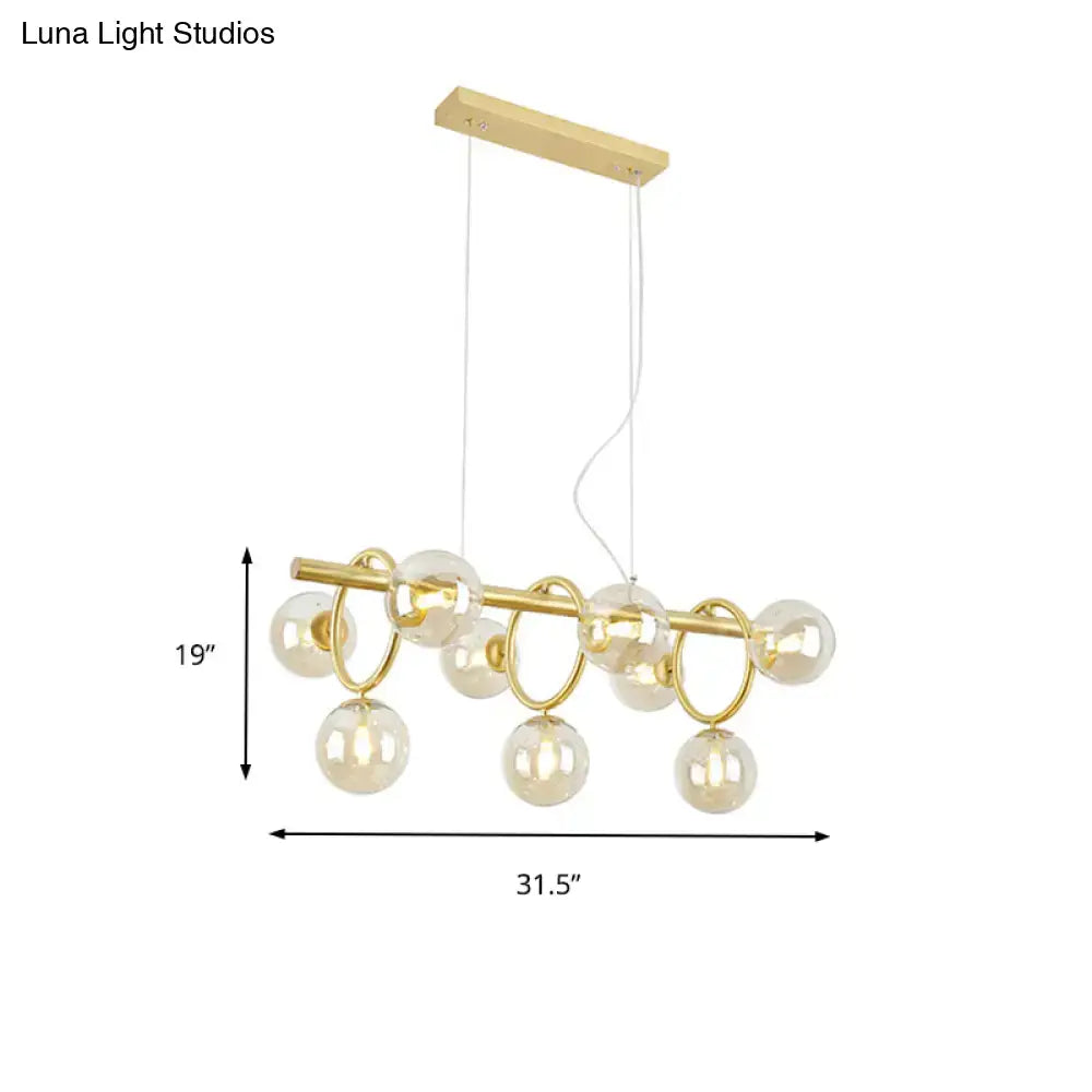 Gold-toned DecorBites™ Nordic pendant light with clear cognac glass spheres and circular metal rings suspended from wood mount