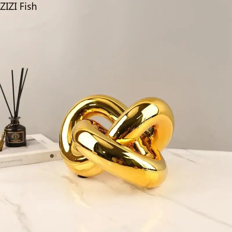 Modern gold-plated knot ornaments featuring a shiny gold ceramic knot sculpture with smooth reflective surfaces for decorbites gold-plated knot decor
