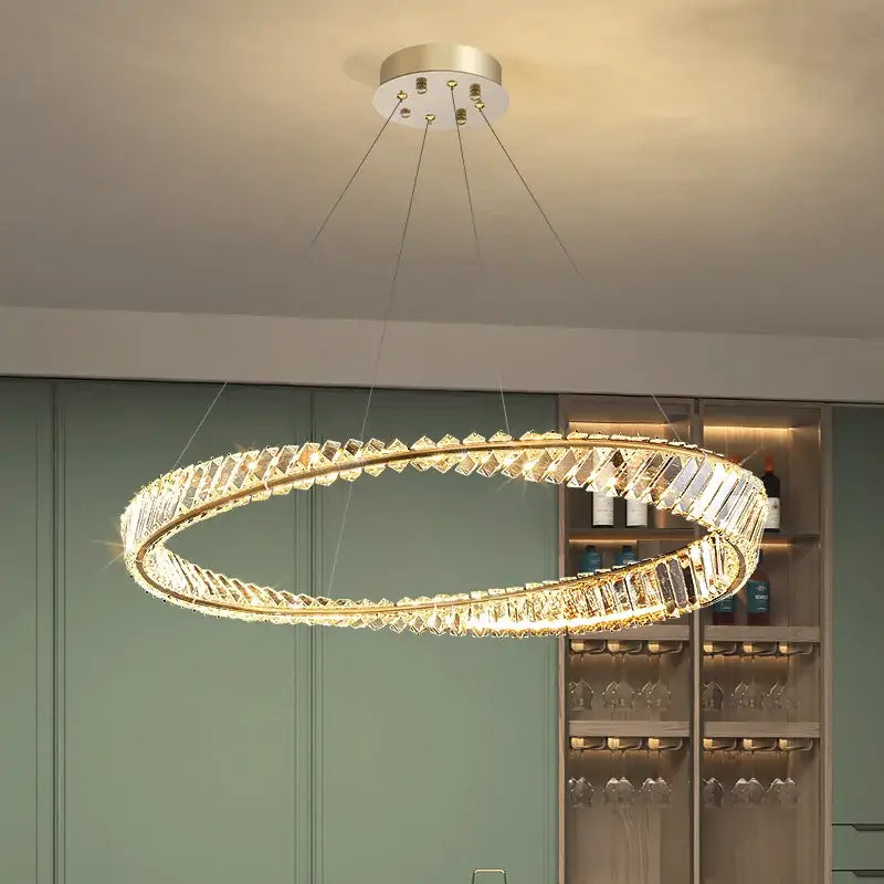 Modern gold plated steel pendant lamp featuring a circular frame with clear crystal facets for dining room decorbites