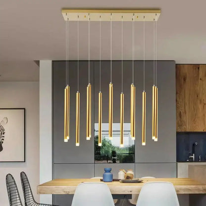 Modern gold-toned cylindrical pendant lights hang from a rectangular fixture in a dining room decorbites elegant chandelier