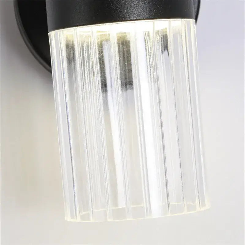 Black wall lamp with clear vertically ribbed glass shade for luxury bedroom bedside lighting