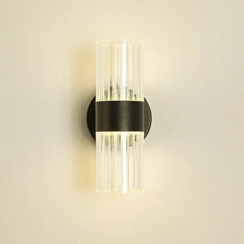 Modern wall lamp with clear ribbed glass shade and black metal base designed for bedroom bedside use