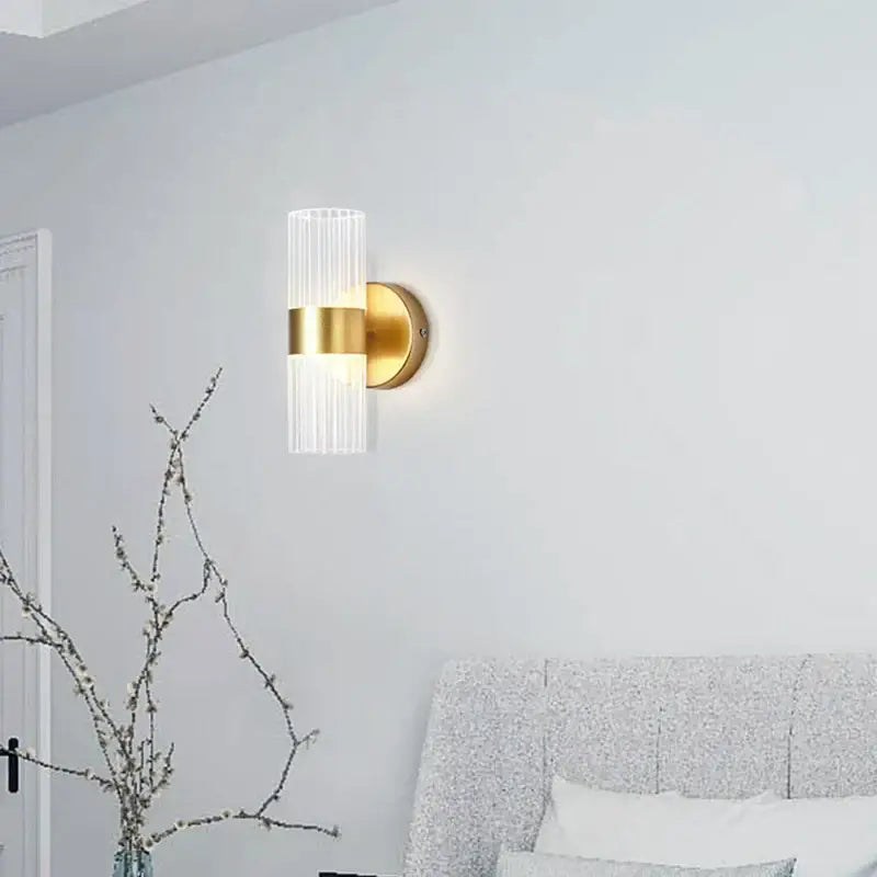 Modern gold wall lamp with a ribbed cylindrical glass shade luxury design for bedroom bedside use