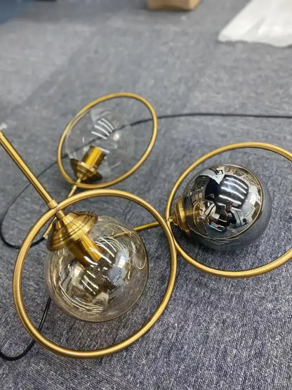 Modern gold pendant light featuring a ring design with three glass globe bulbs for dining room lighting