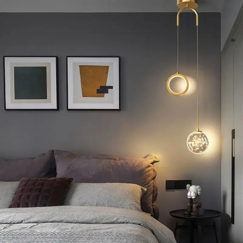 Modern gold ring led pendant light with crystal globe and decorbites gold ring design hanging above the bed