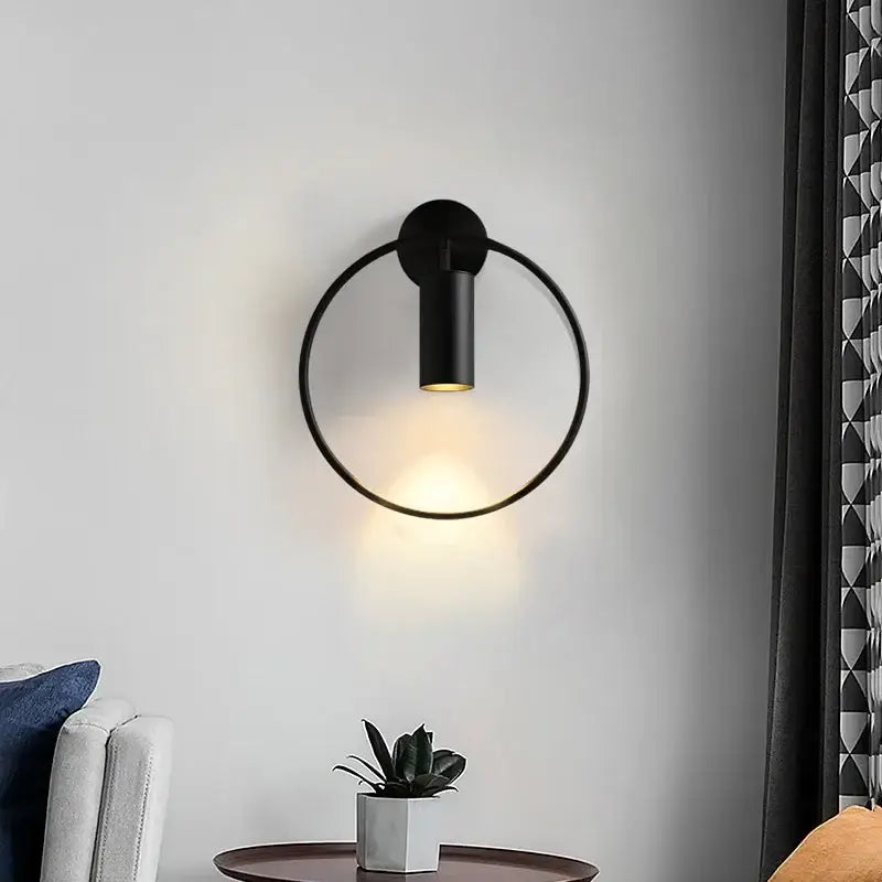 Modern gold ring led wall sconce light with black circular minimalist design and warm ambient lighting for bedroom use