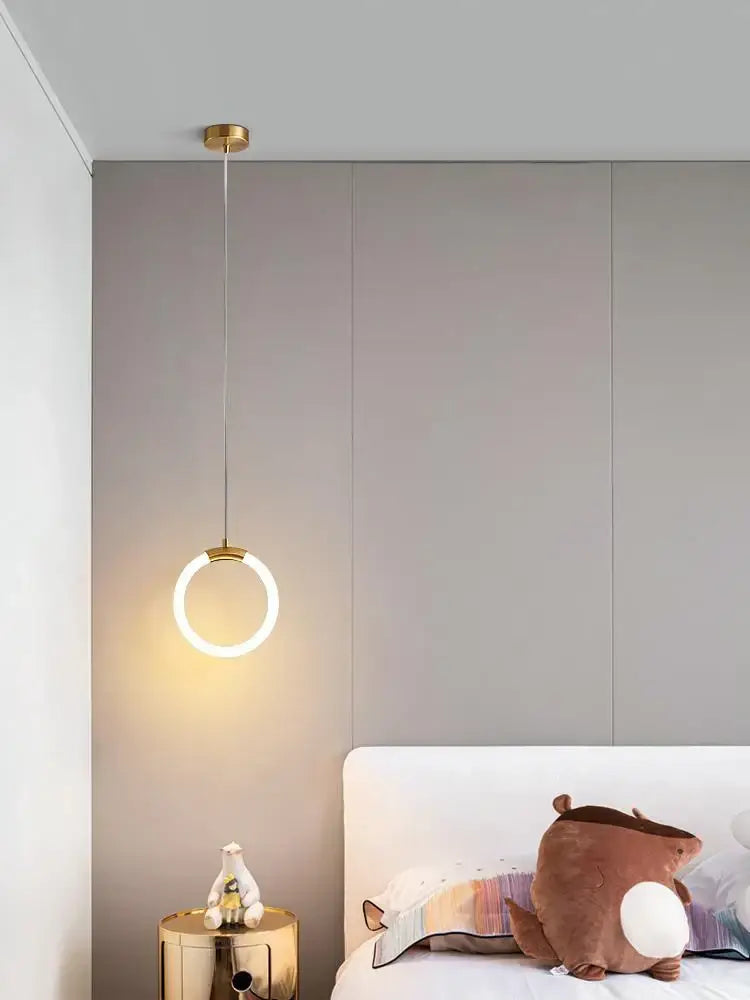 Modern gold ring pendant light with a sleek minimalist design in gold tone above the bed by decorbites pendant lights
