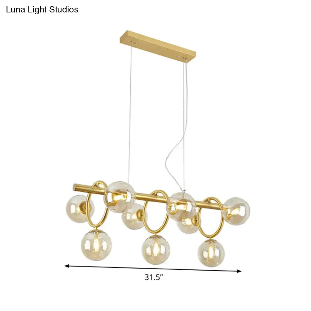 Modern gold round pendant chandelier with cognac glass spheres and circular metal rings in linear design suspension