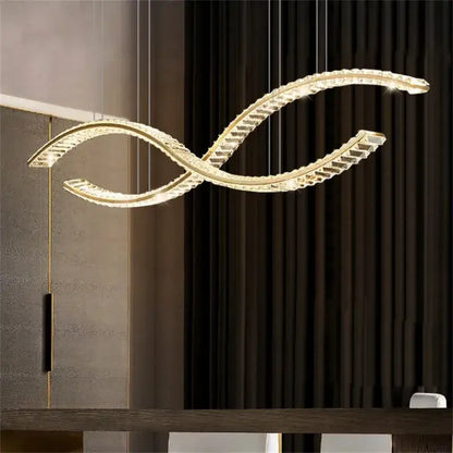 A modern gold s-shaped decorbites crystal led pendant light fixture with clear crystal accents for dining rooms