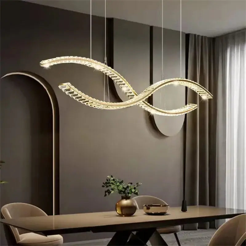 A modern gold-toned decorbites crystal led pendant with a sleek s-shaped design for dining room lighting