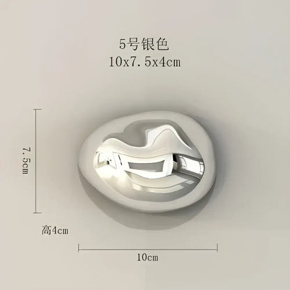 Silver-colored oval metal pendant with a smooth reflective surface and abstract design for stone wall ornaments decor