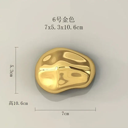 A smooth polished gold stone wall ornament with glossy finish and irregular contours for modern living room decor