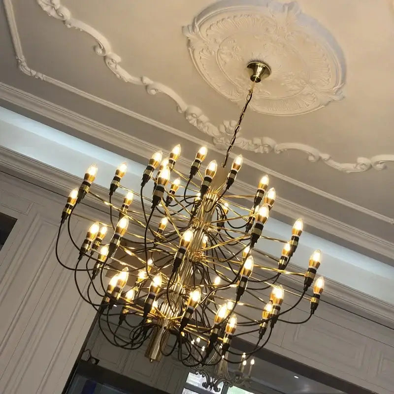 Modern gold silver chandelier with 50 exposed bulbs and black wiring suspended from ornate ceiling medallion