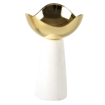 A sleek gold-toned ceramic dessert bowl with a wavy rim on a white marble pedestal for decorbites golden tray
