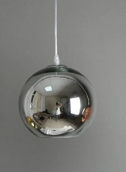 A sleek spherical chrome glass bubble ball pendant light with reflective surface for modern kitchen decorbites pendant lights