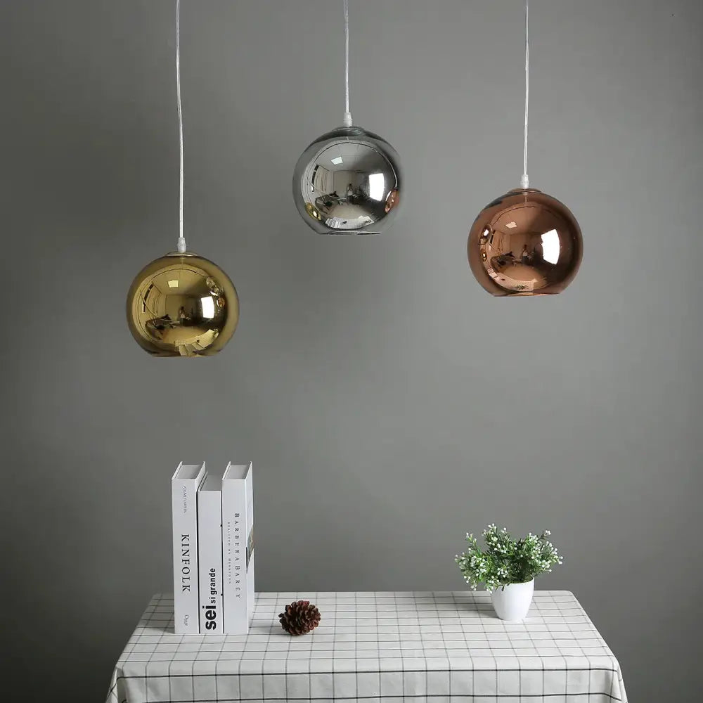 Three spherical pendant lights in gold silver and rose gold glass bubble ball design hang above a kitchen table