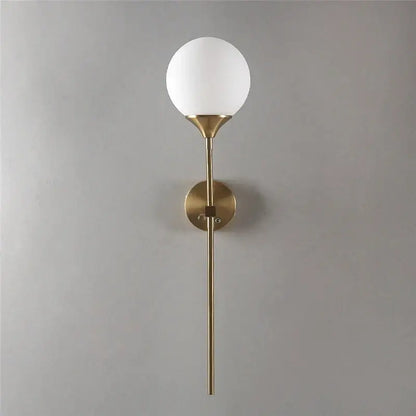 A sleek brass wall sconce with a frosted white spherical decorbites glass lampshade wall for bedroom light