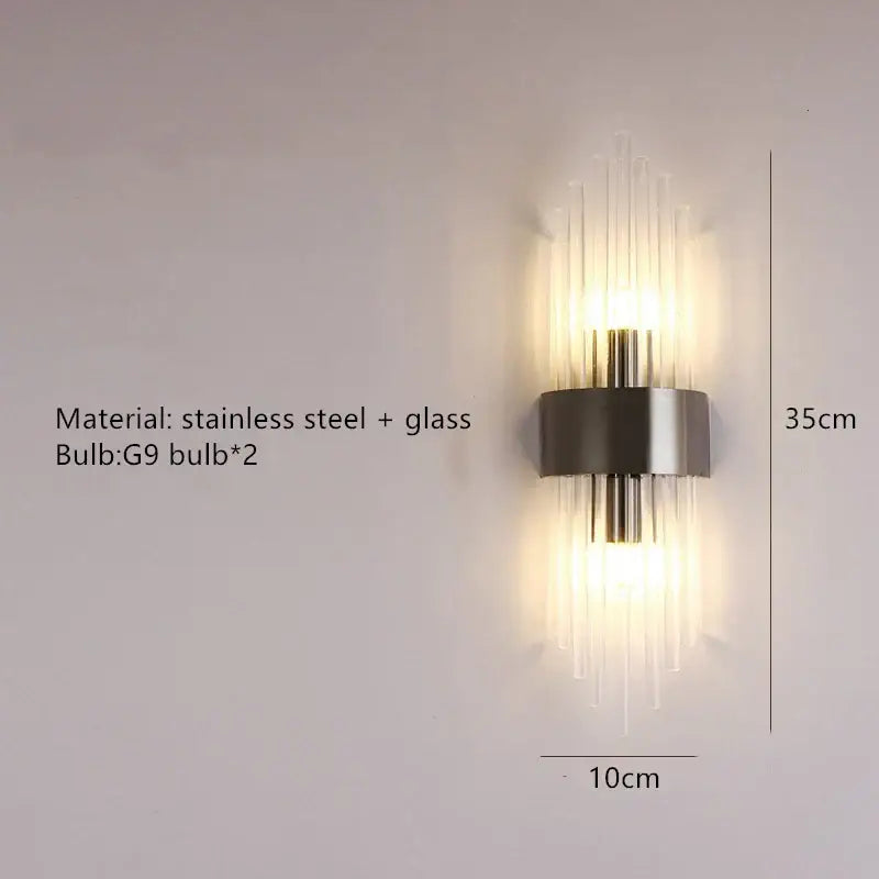 Modern gold stainless steel wall lamp with clear crystal vertical rods emitting warm light for bedroom sconce