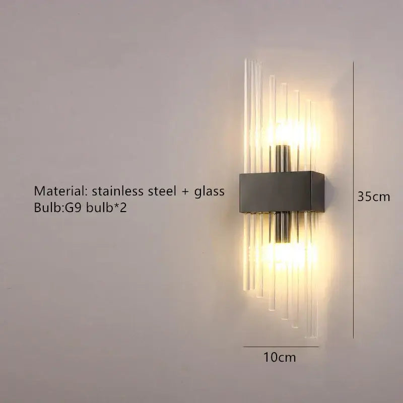 Modern gold stainless steel wall lamp with clear crystal vertical rods emitting warm light for bedroom sconce