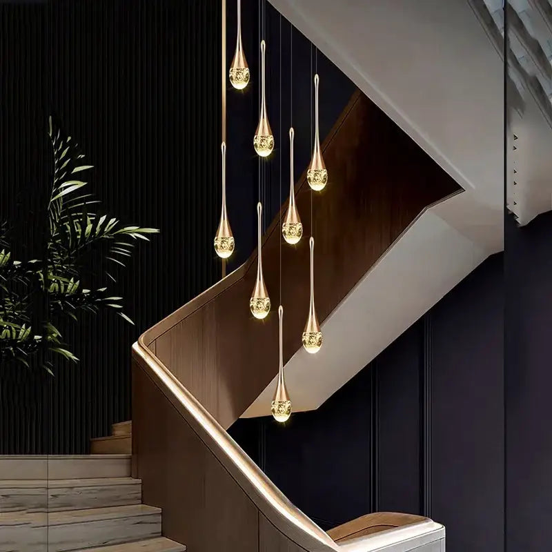 Modern gold teardrop crystal pendant light with elegant crystal accents hanging above a dining room staircase