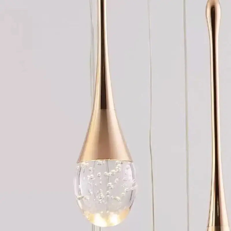 Modern gold teardrop crystal pendant light with clear glass globe and floating bubbles for dining room illumination