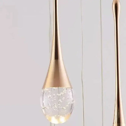 Modern gold teardrop crystal pendant light with clear glass globe and floating bubbles for dining room illumination