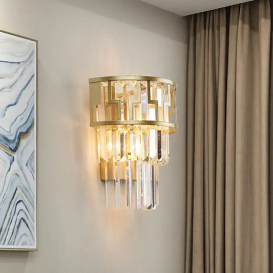 Modern gold tiered bedside wall lamp with geometric metal frame and cascading clear crystal prisms for bedroom use