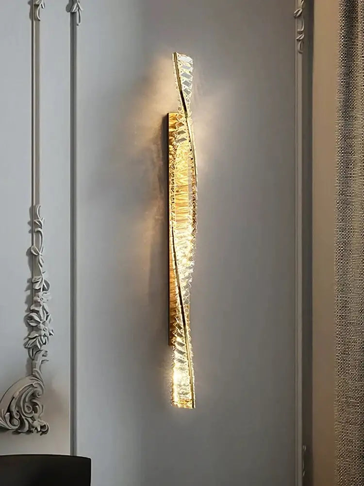 Modern gold twisted crystal wall sconce with decorbites crystal wall accents emitting warm bedroom light