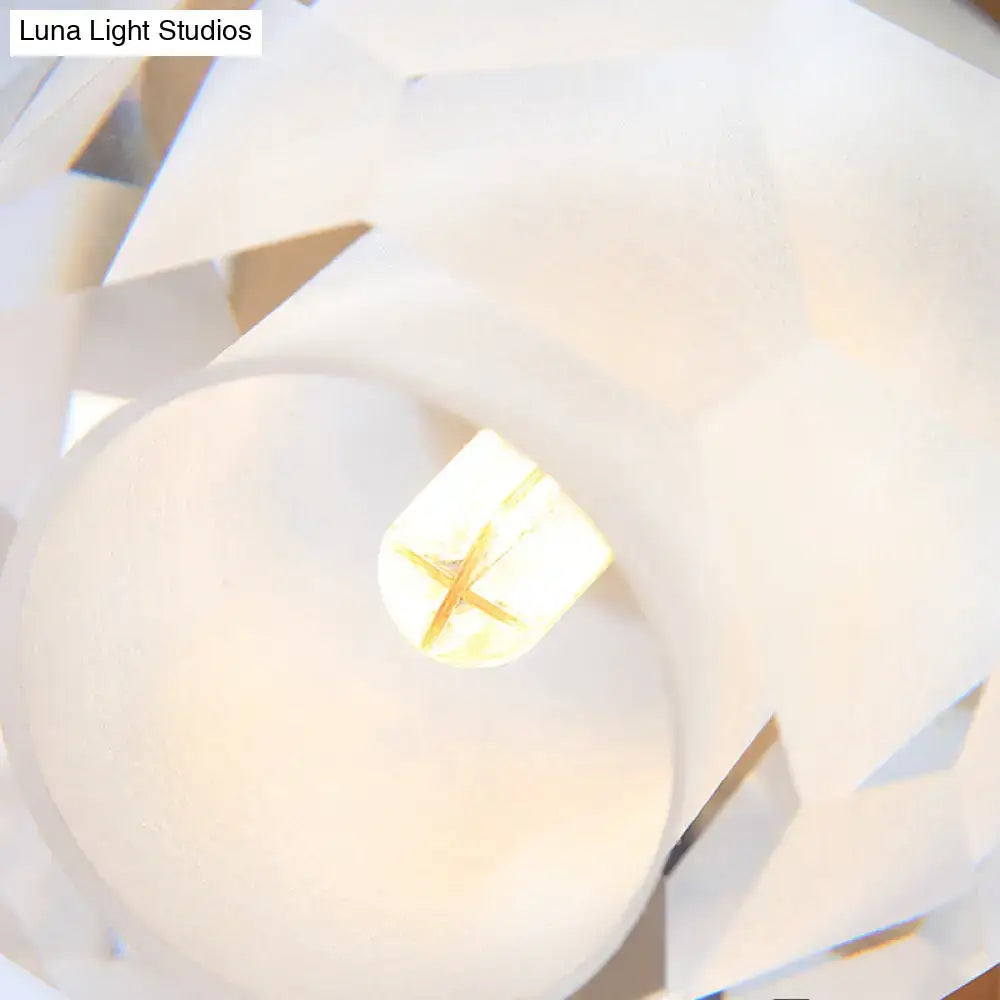 Modern gold wall lamp with faceted globe shade featuring a white geometric paper lantern and glowing light bulb center