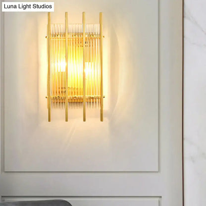 Modern gold wall sconce with clear crystal vertical rods and warm glowing light for hallway illumination