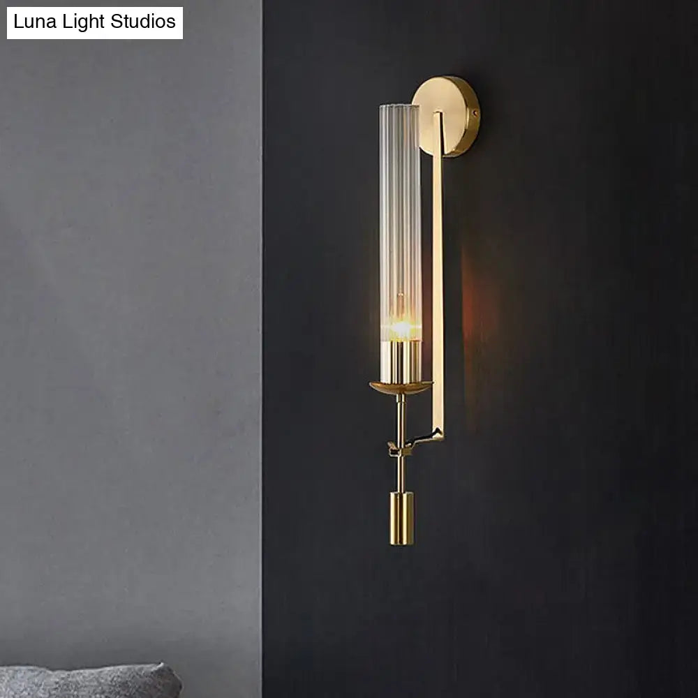 Modern gold wall sconce with clear glass shade featuring a tall cylinder and sleek metallic accents for bathroom light