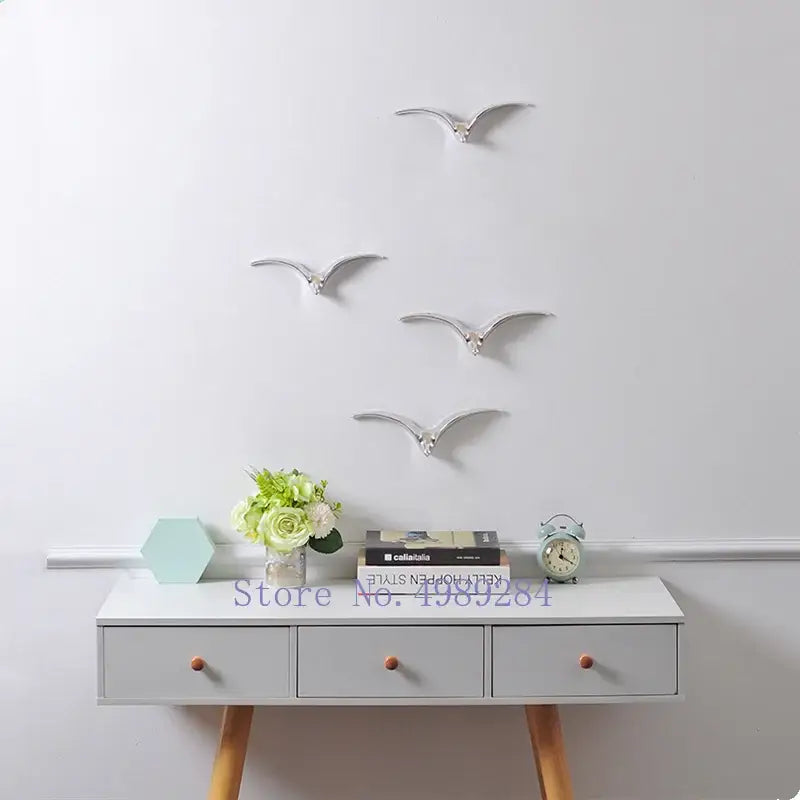 Silver metallic bird wall decor with sleek minimalist design complementing modern gold and white ceramic pendant wall decor