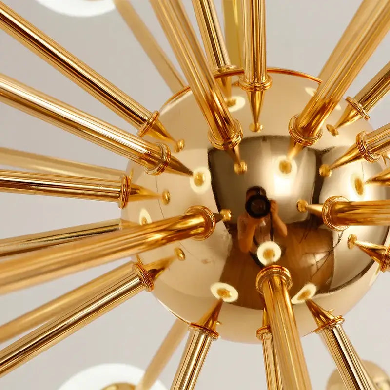 Modern golden acrylic molecule chandelier featuring a golden brass design with radiating rods and reflective glass globe center