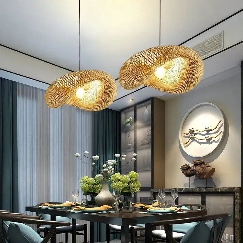 Two golden bamboo woven chandeliers pendant light hang above a dining table creating a modern woven chandelier tea room ambiance