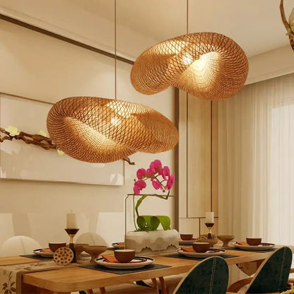 Two golden bamboo woven chandelier pendant lights hang over a dining table casting a warm glow in a tea room setting