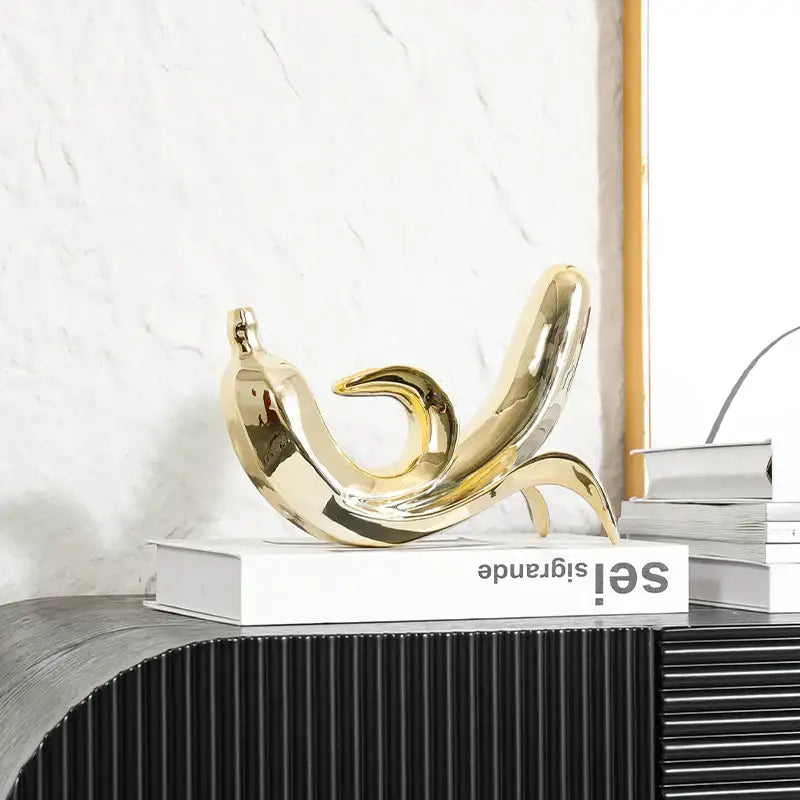 Shiny gold ceramic golden banana figurine with smooth reflective surface and elegant curved form for living room decor