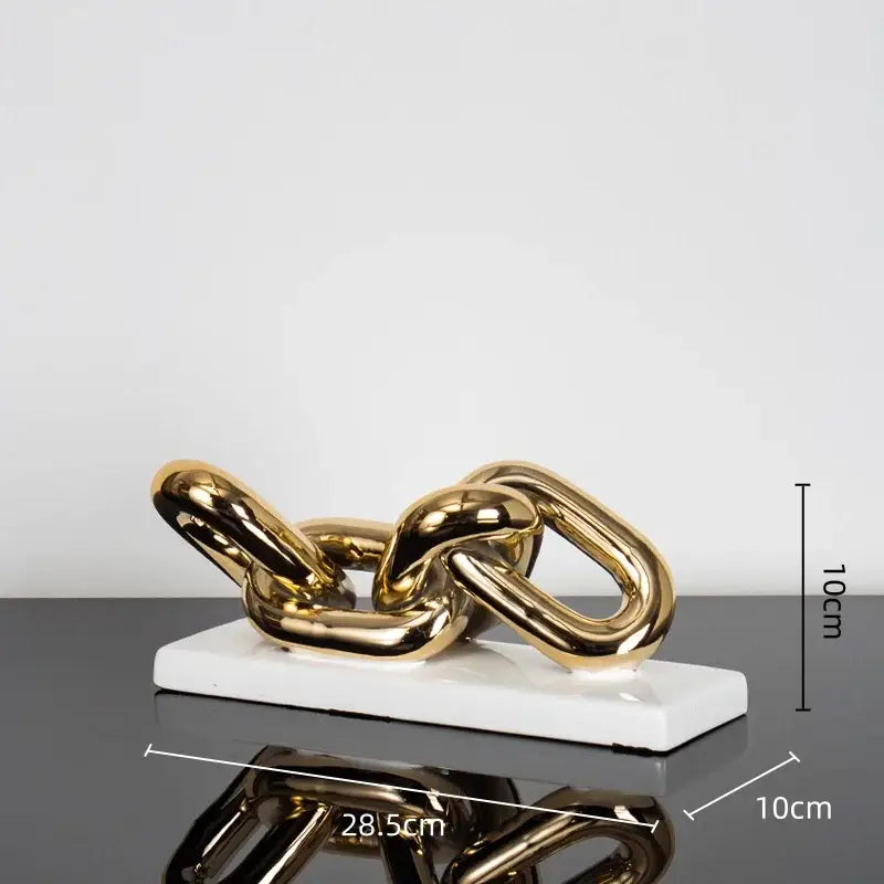 Modern golden chain home decoration figurine in metallic finish resting on a white ceramic base for living room decor