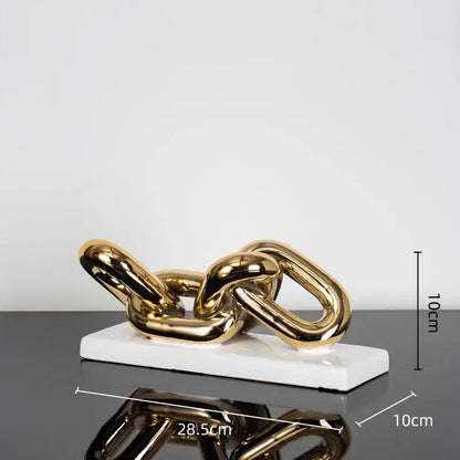 Modern golden chain home decoration figurine in metallic finish resting on a white ceramic base for living room decor