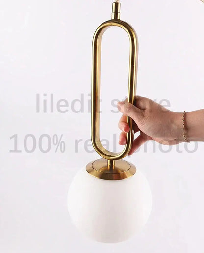 Modern golden glass ball pendant light with sleek oval metal frame and white glass shade by decorbites for kitchen decor
