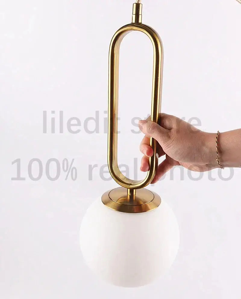 Modern golden glass ball pendant light with sleek oval metal frame and white glass shade by decorbites for kitchen decor