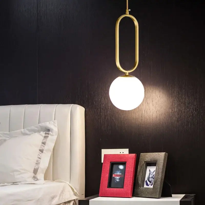 Modern golden glass ball pendant light with gold-toned oval metal frame and frosted glass globe by decorbites
