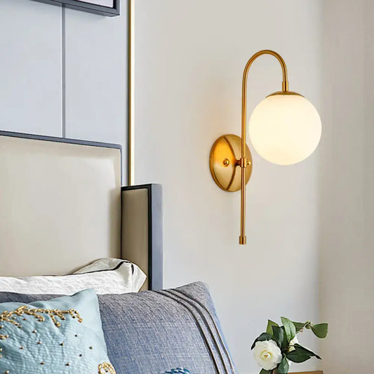 Modern golden gooseneck wall sconce with a frosted glass ball shade and curved arm for bedroom lighting
